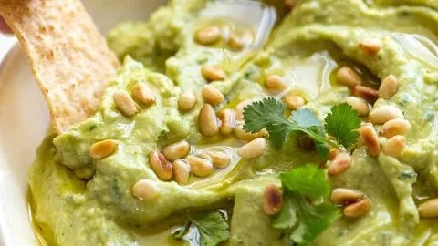 Delicious avocado dip served in a bowl with fresh ingredients.