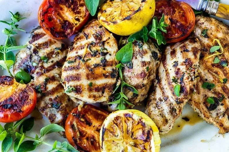 Grilled lemon herb chicken served with fresh herbs and lemon slices.